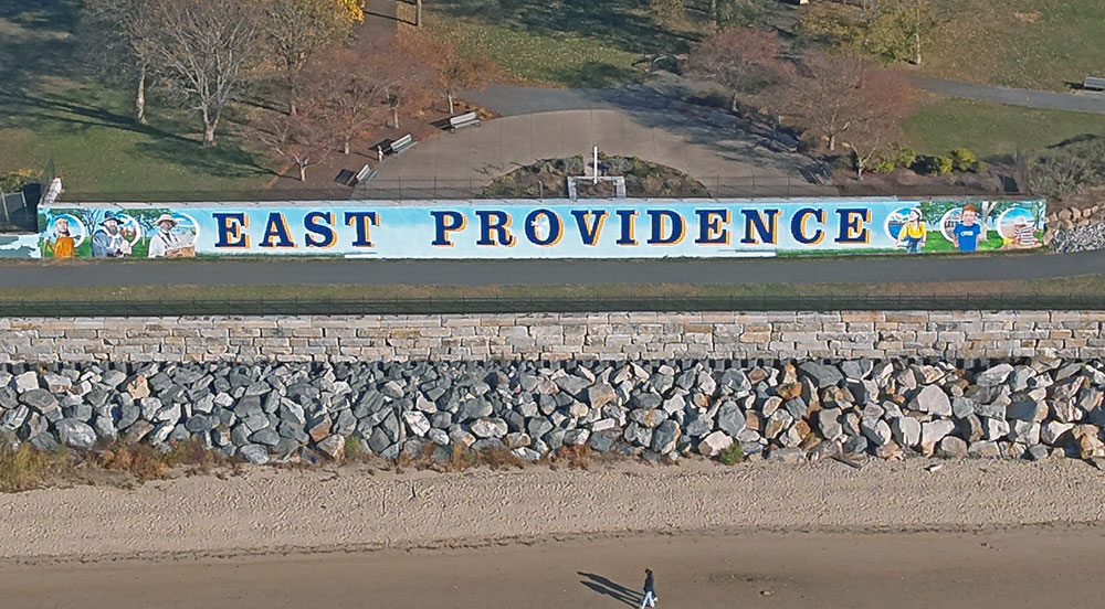 Explore the rich history and vibrant future of East Providence through a stunning 200-foot mural on the Crescent Park Beachfront Wall. Featuring Native heritage, local landmarks, and iconic symbols, this artwork celebrates the city’s cultural resilience and scenic beauty